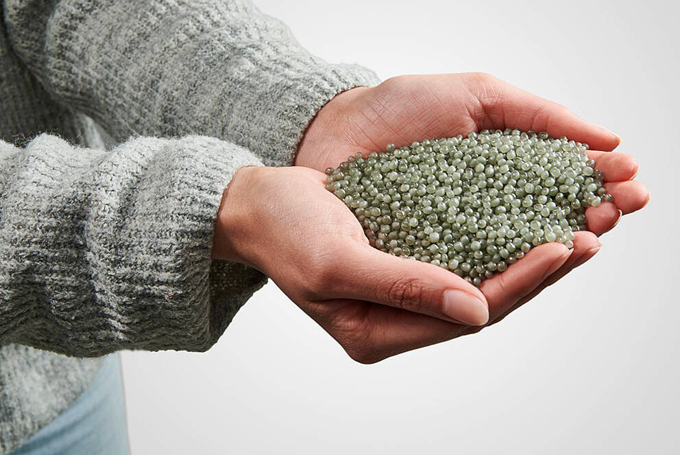 Hands presenting recycled plastic granules from KURZ embossed foils